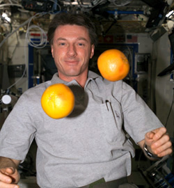 Astronaut C. Michael Foale auf der ISS. Vor ihm schweben zwei Grapefruits