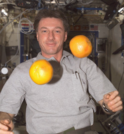 Astronaut C. Michael Foale on the ISS, with two grapefruits hovering in front of him.